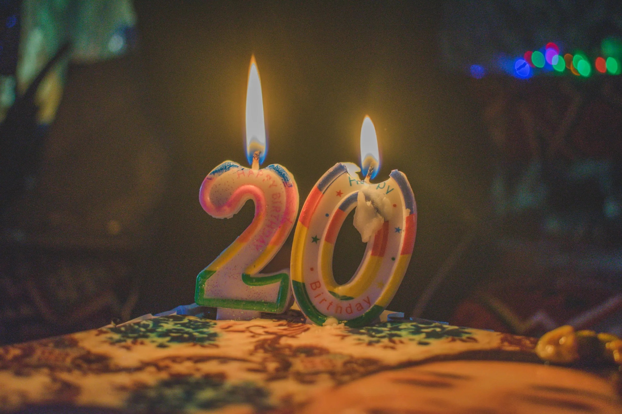 A decorated birthday cake featuring two candles shaped like the number twenty, symbolizing a 20th birthday celebration.