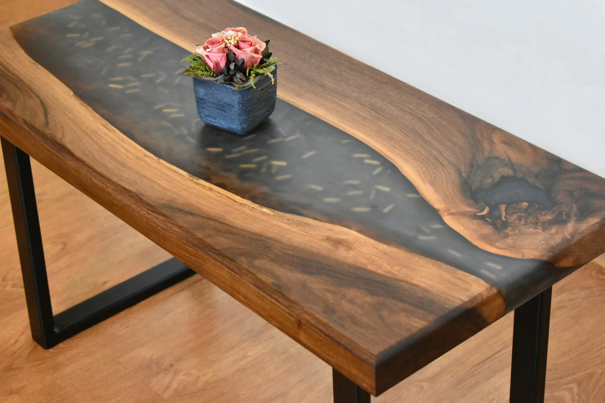 A wooden table featuring a decorative flower vase at its center, adding a touch of elegance to the setting.